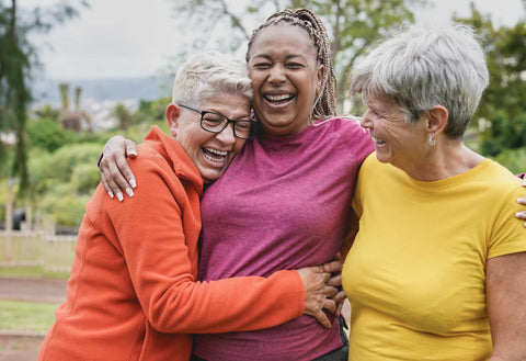 Three women hugging and laughing together in a park