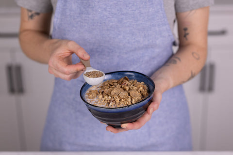 Person holding a bowl of cereal and adding a spoonful of Natura Fiber