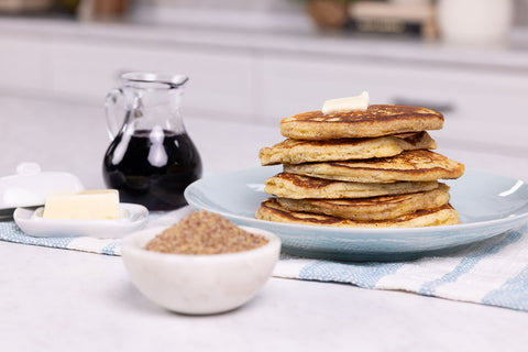 Stack of pancakes on a plate with syrup, butter, and Natura Fiber in the foreground.