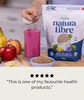 Person adding fiber to a smoothie with Natura Fibre packaging and ingredients on a table. 5 Star review reading, "This is one of my favourite health products."