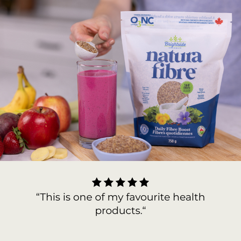 Person adding fiber to a smoothie with Natura Fibre packaging and ingredients on a table. 5 Star review reading, "This is one of my favourite health products."