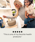 Woman holding a child in a kitchen with a Natura Fiber bag in the foreground. A 5-star review reading, "This is one of my favorite health products."